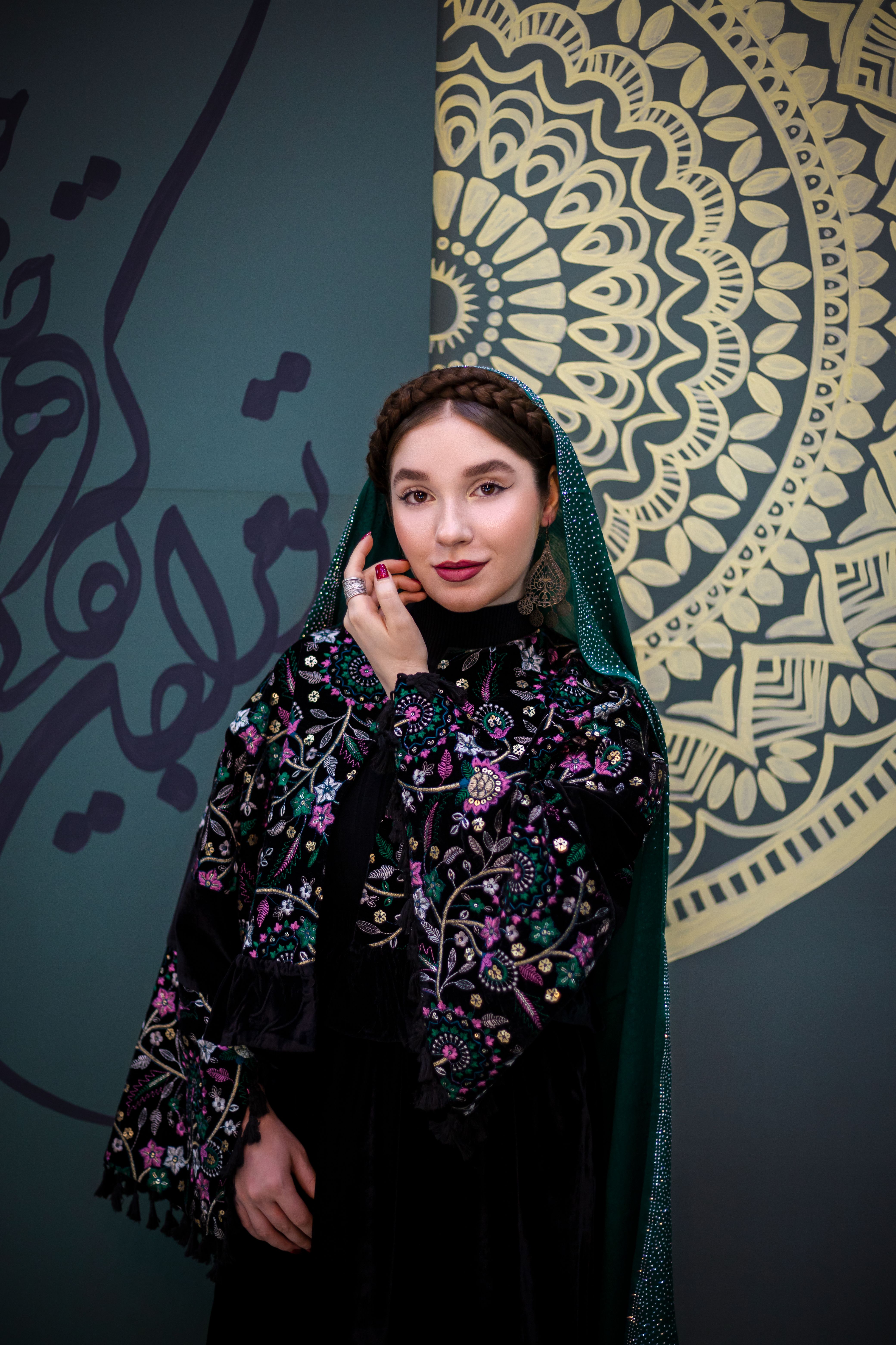 Woman in ornate traditional clothing, intricate patterns, thoughtful pose.