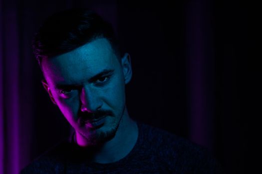 Artistic portrait of a male with vibrant blue and pink lighting creating a moody atmosphere.