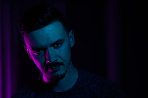 Free Artistic portrait of a male with vibrant blue and pink lighting creating a moody atmosphere. Stock Photo