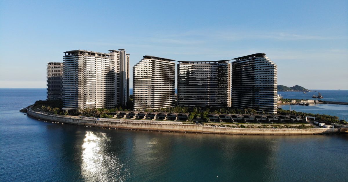 Aerial view of sleek modern skyscrapers by the ocean under clear blue skies.
