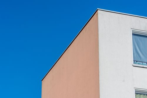 Free A minimalist building corner with contrasting colors set against a clear blue sky. Stock Photo