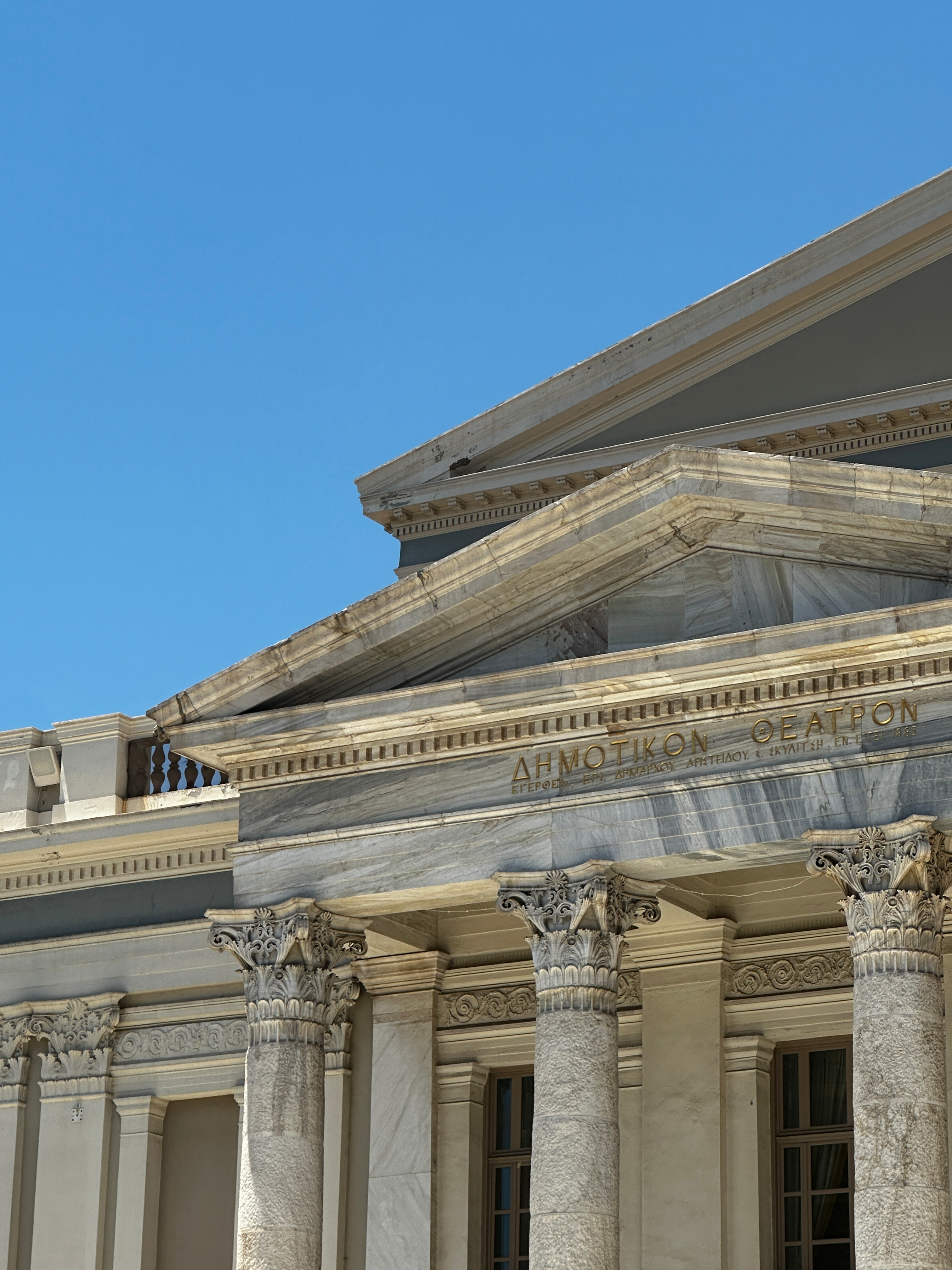 Elegant classical columns of a historic building in Athens, Greece under clear blue skies.