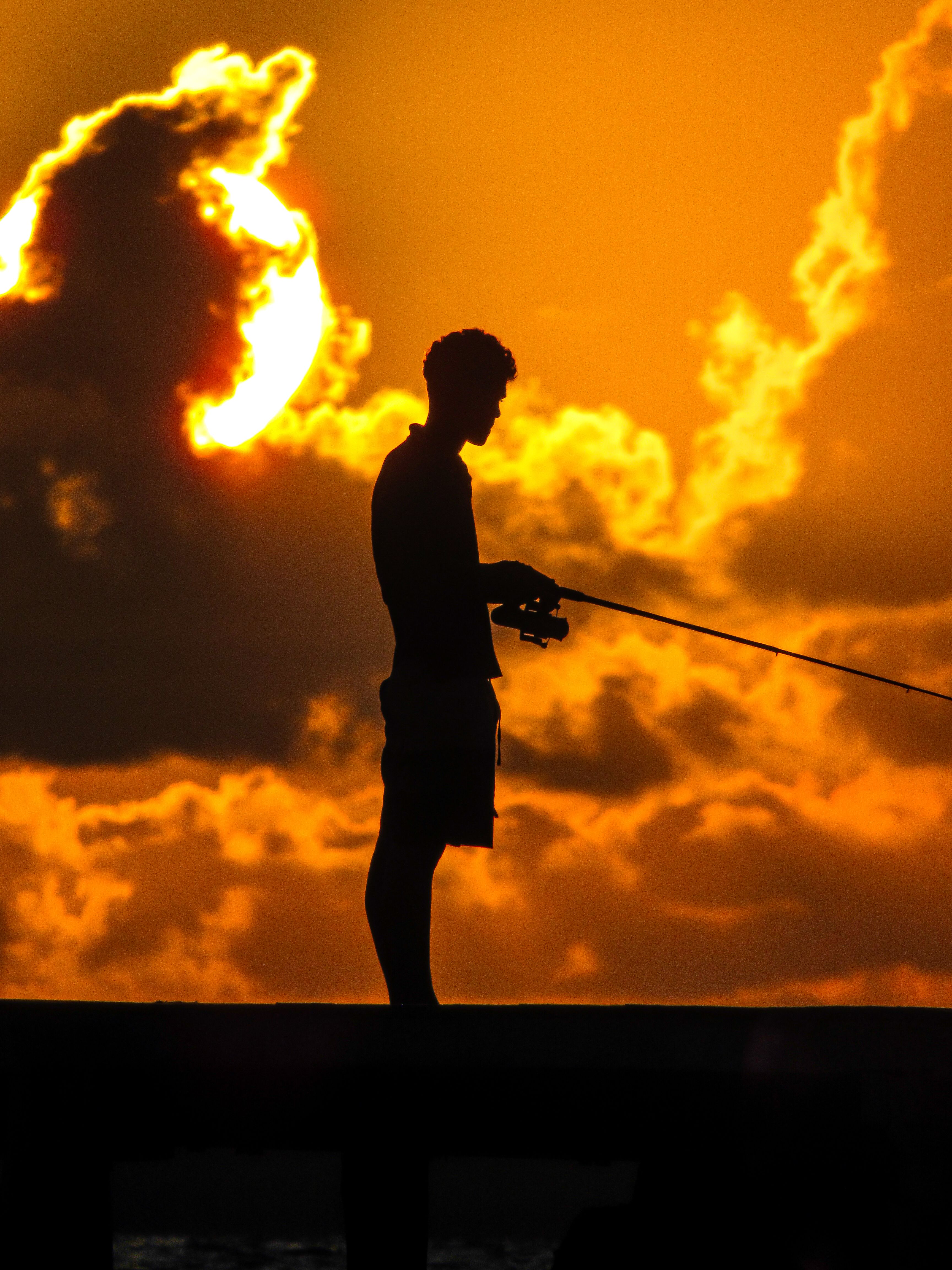 Silhouette of a Person Fishing at Sunset · Free Stock Photo