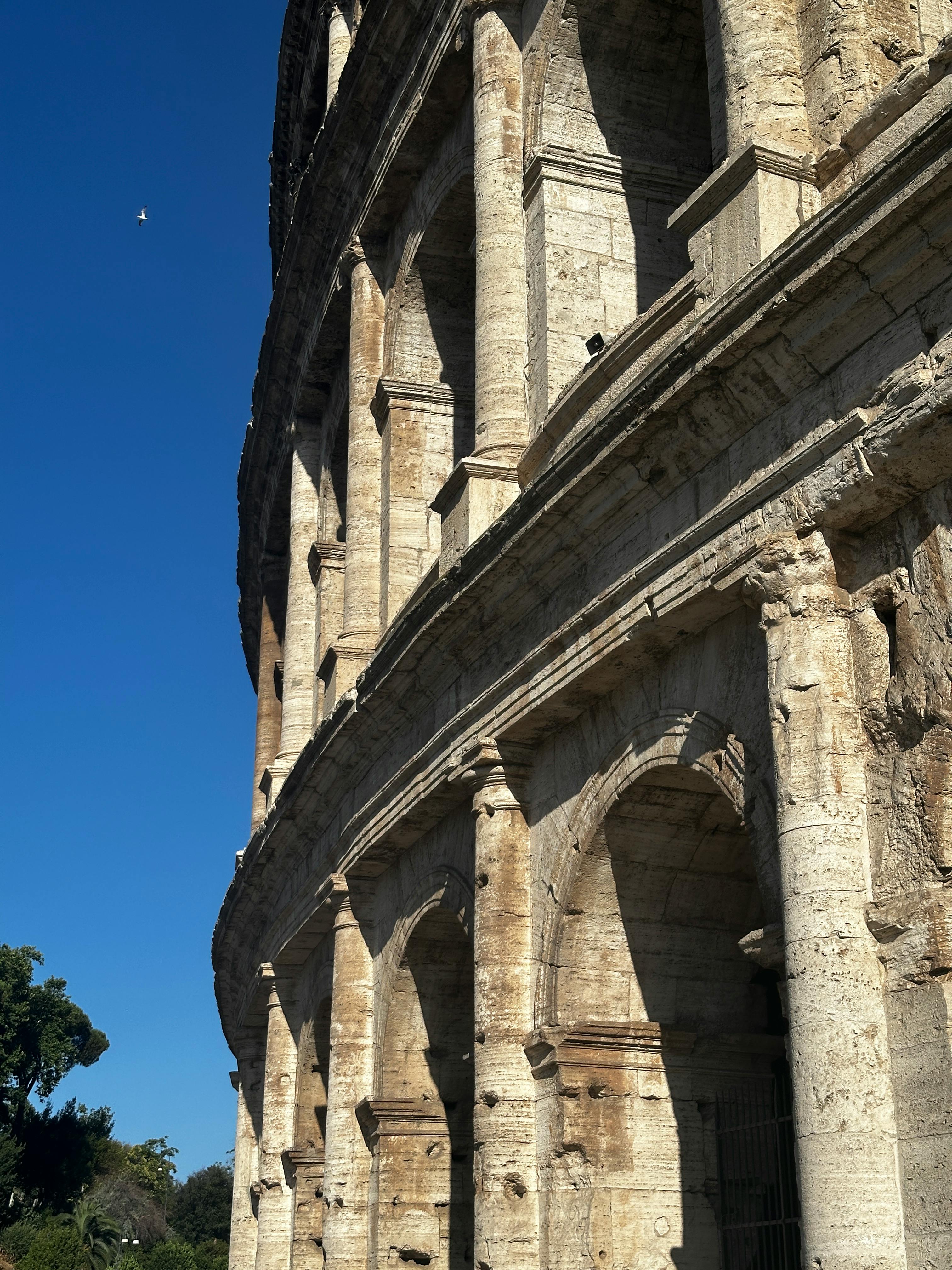 Kostenlos Nahaufnahme des Kolosseums in Rom vor einem strahlend blauen Himmel, die die ikonische römische Architektur zur Schau stellt. Stock-Foto