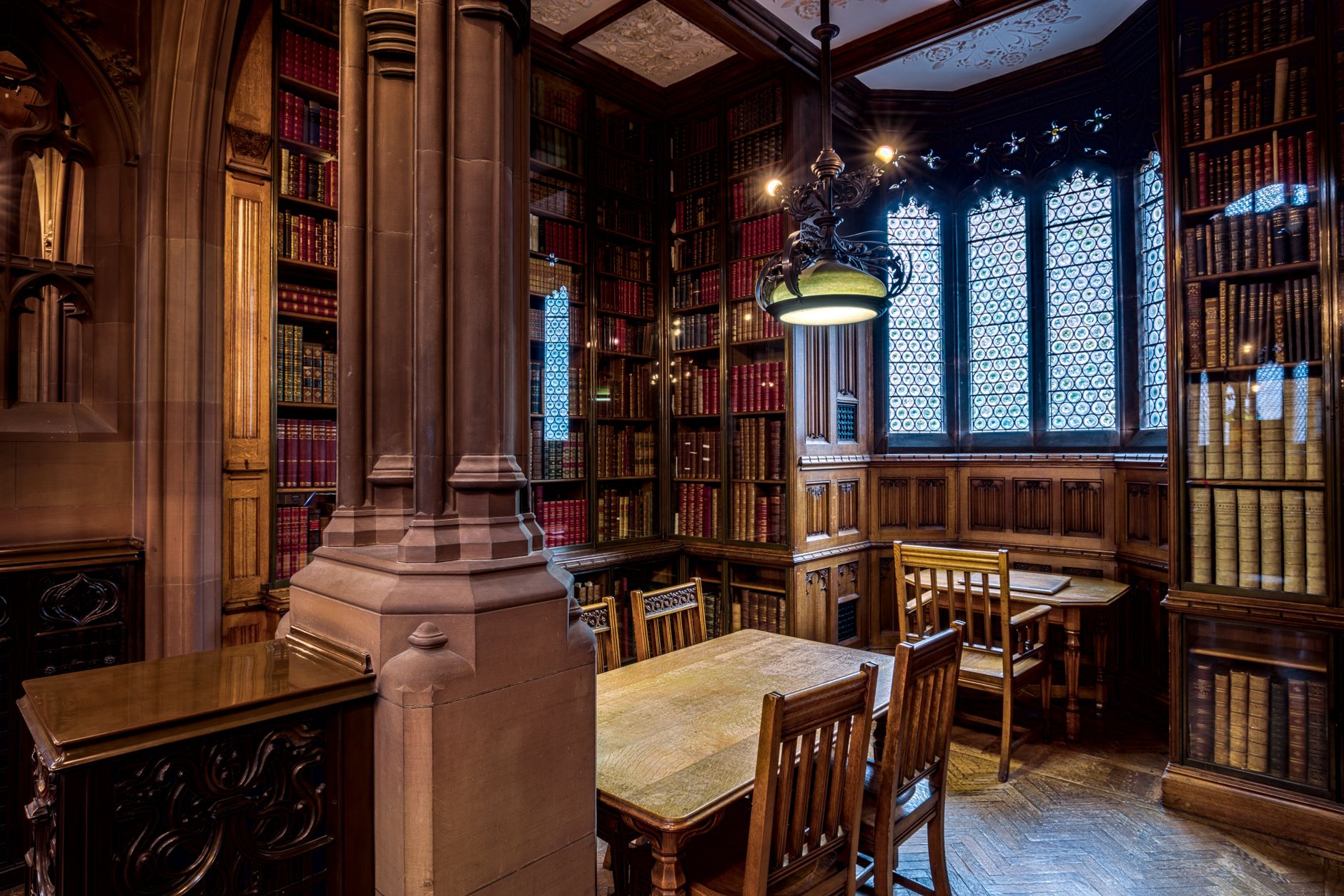 A serene, sunlit interior of a prestigious university library with classic architecture and leather-bound books.