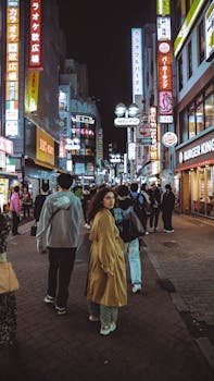 Vibrant Tokyo street at night with neon lights and pedestrians, capturing the city's lively atmosphere.