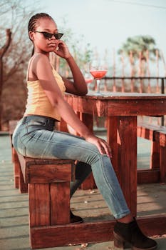 一位年轻女子坐在户外的木凳上，时尚地喝着饮料