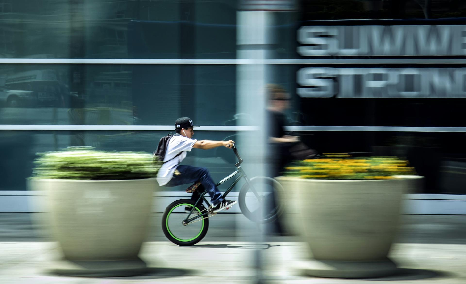 Child riding a BMX bike quickly through an urban setting, blurred motion reflects speed.