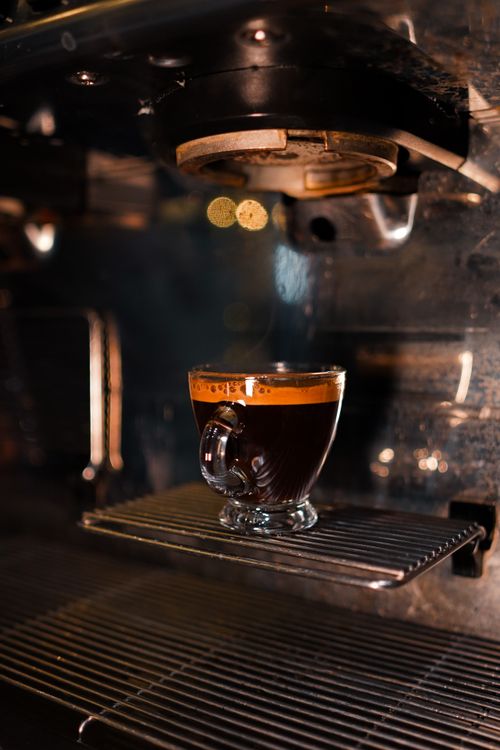 Free Steaming espresso served in a café glass mug on espresso machine, vibrant and warm ambiance. Stock Photo