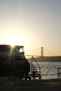 Serene view of a ship by the Bosphorus Bridge during sunset in İstanbul, Türkiye.