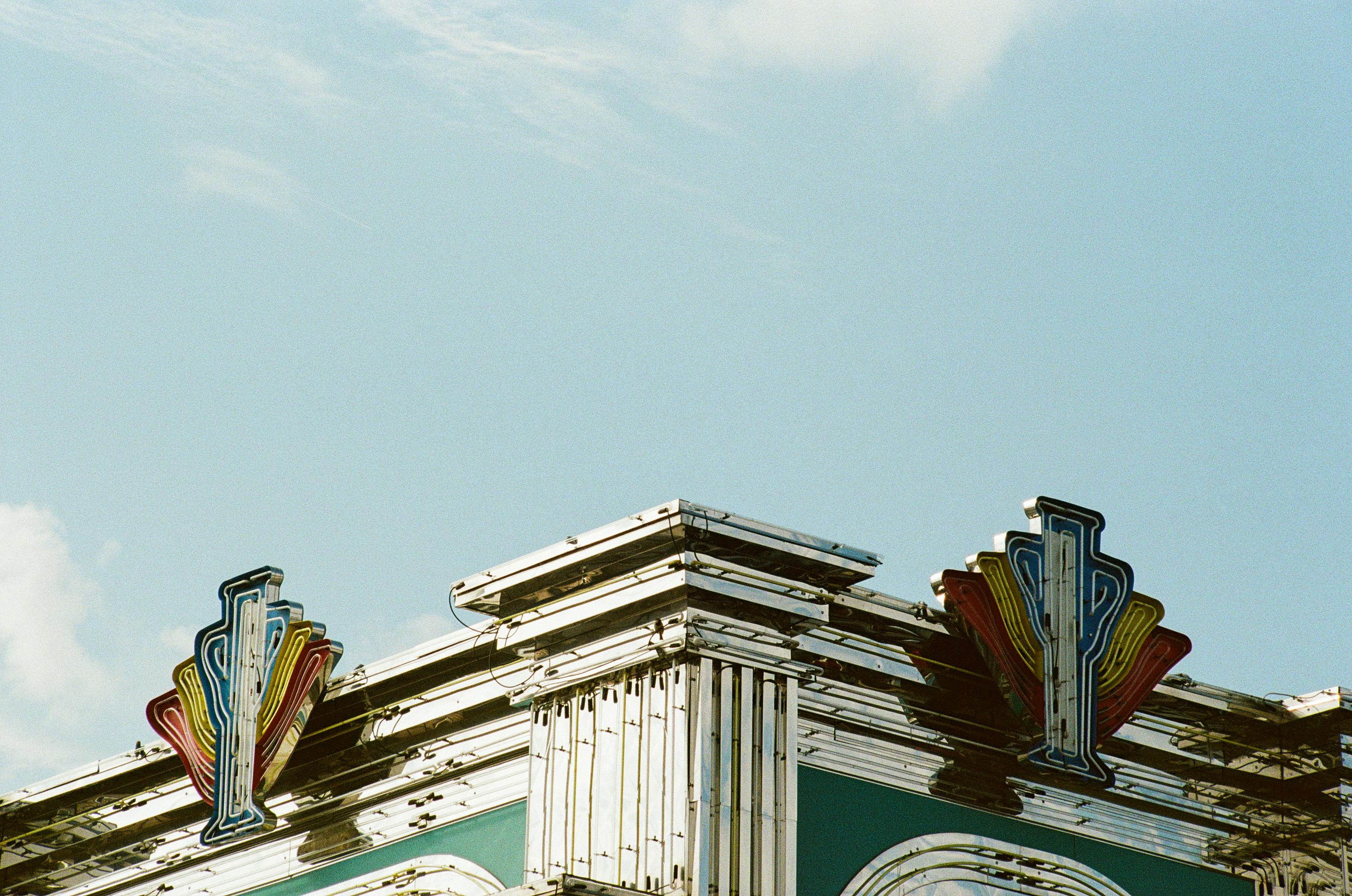 Ilmainen Art Deco -rakennusnurkkaus, jossa on värikkäitä retro-neonkylttejä kirkasta sinistä taivasta vasten. Kuvapankkikuva