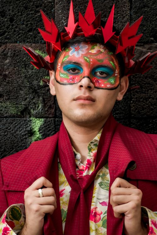 Free Portrait of a man wearing a colorful mask and a red suit with floral patterns, exuding a festive and artistic vibe. Stock Photo