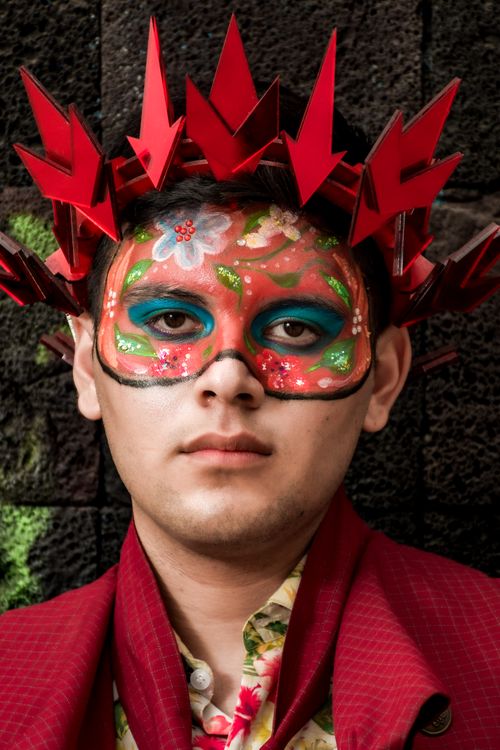 Free Close-up of a person wearing a colorful artistic mask and red headpiece, displaying creativity and cultural expression. Stock Photo
