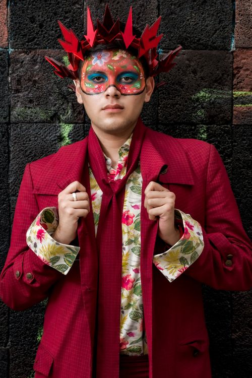 Free A person in a vibrant red costume with an artistic mask, exuding a festive and creative vibe. Stock Photo