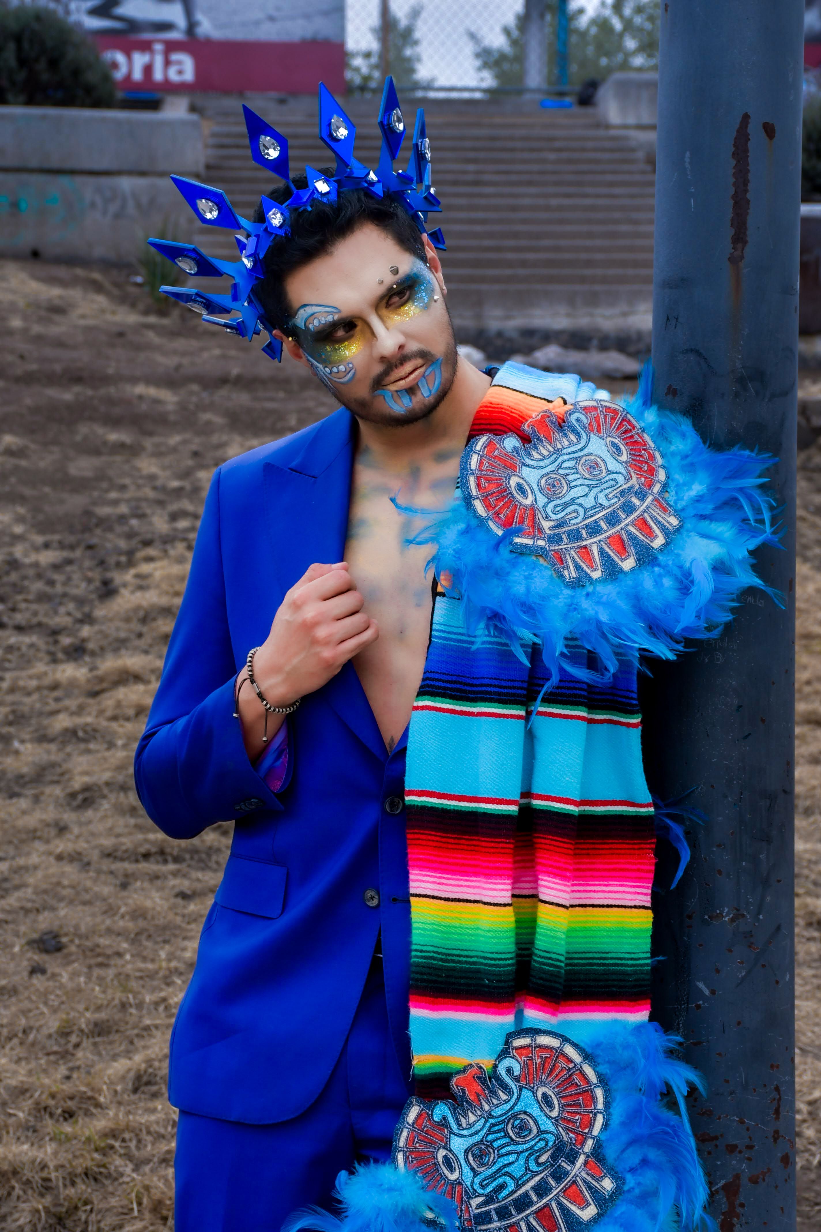 Colorful portrait of a person in a vibrant costume with Aztec motifs outdoors.
