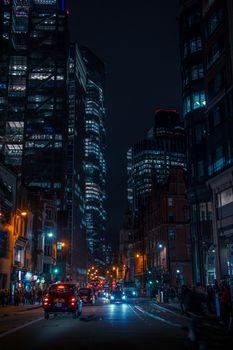 Dynamic night view of London's illuminated skyscrapers and bustling street time.