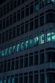 A modern office building in London illuminated at night with glowing blue windows.