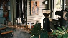 Warm coffee shop interior featuring an espresso machine and common brewing equipment.