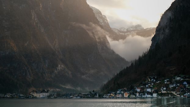 Une vue tranquille du village de Hallstatt niché au pied de montagnes majestueuses sous un ciel nuageux.