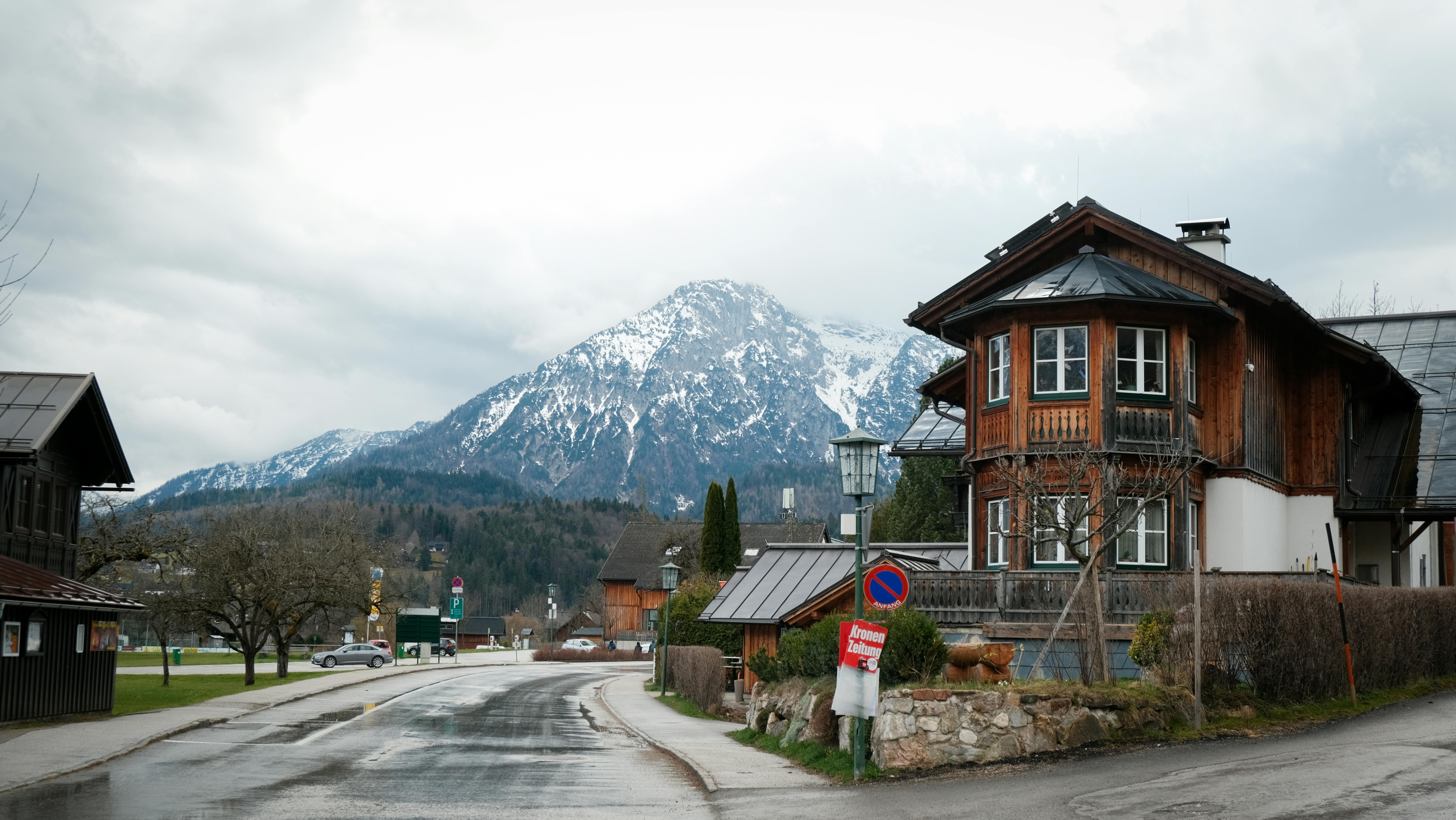 Rustic wooden houses against a scenic snowy mountain backdrop in a quaint alpine village.