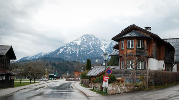 Rustic wooden houses against a scenic snowy mountain backdrop in a quaint alpine village.