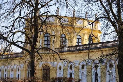 Free Beautiful view of the Orangerie in Kassel, Hessen, with tree branches framing the historic architecture in spring sunlight. Stock Photo