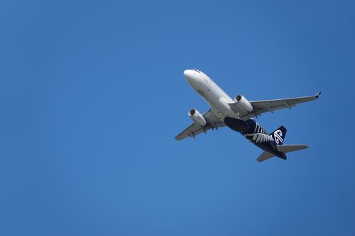 Free Airplane flying against a clear blue sky, capturing pristine aviation scene in New Zealand. Stock Photo