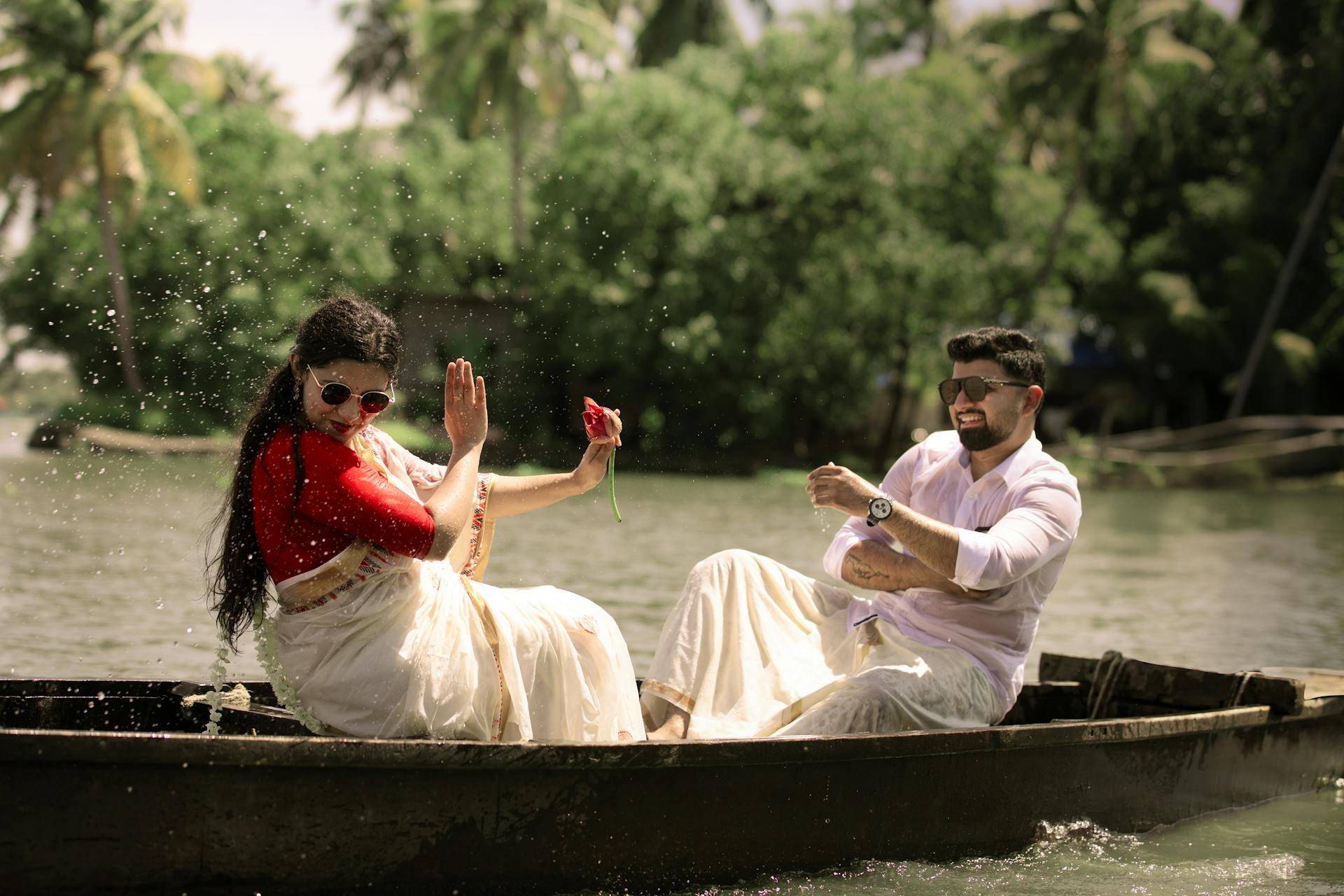 A couple wearing traditional Indian attire enjoys a boat ride in the lush backwaters of Kerala.
