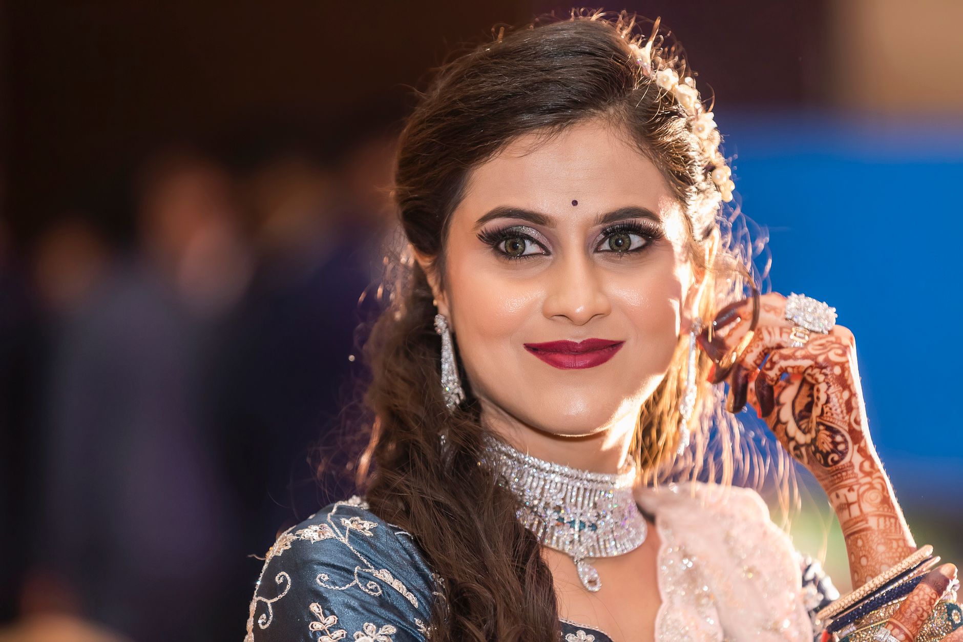 Beautiful woman in Indian attire with henna tattoos, jewelry, and a confident smile.