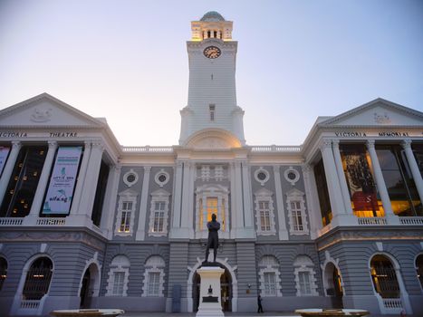 The iconic Victoria Theatre and Concert Hall in Singapore at sunset with a statue in front.