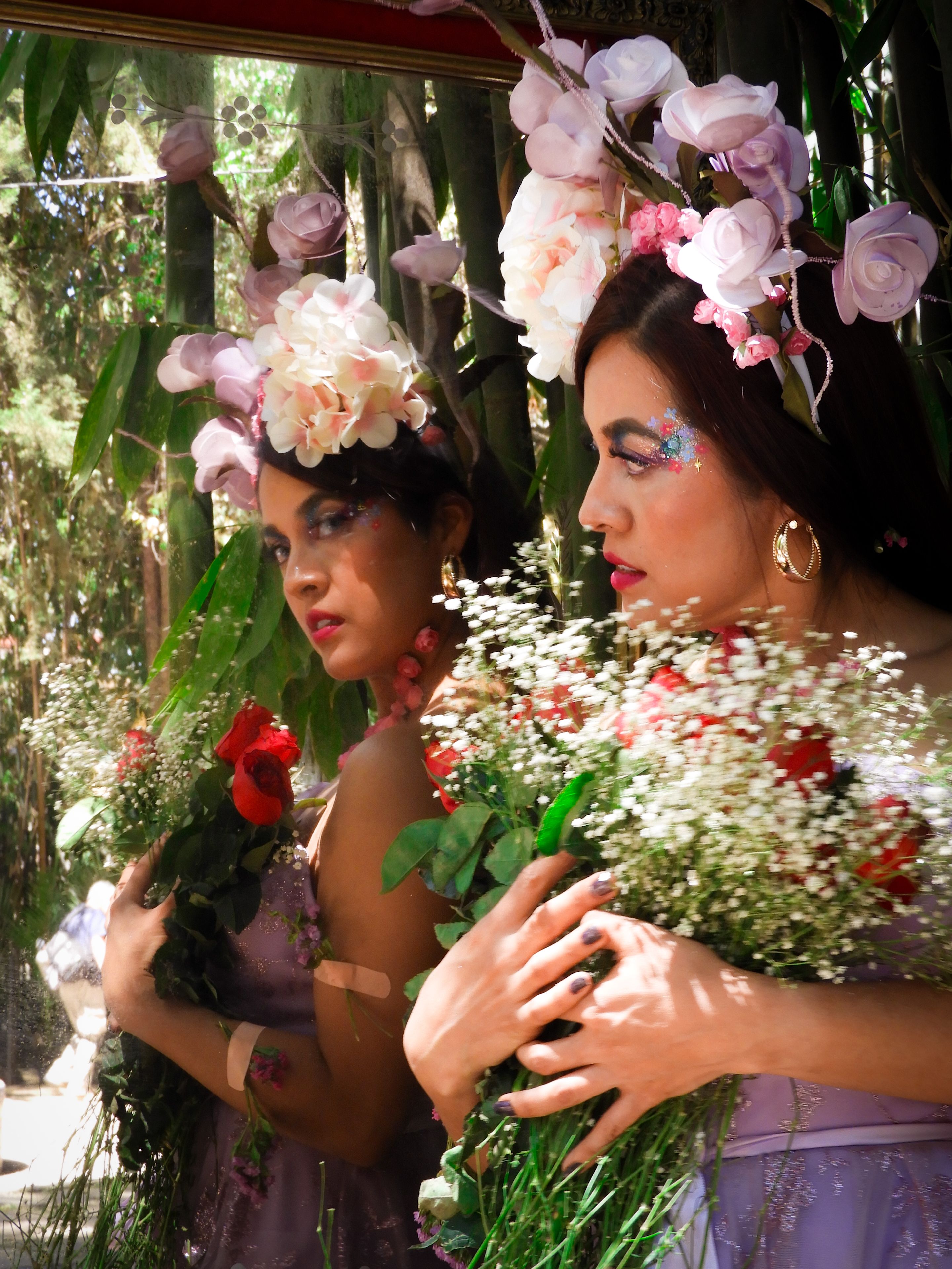 Fotomural Mujer con tocado floral sosteniendo un ramo, reflejándose serenamente en un espejo al aire libre.