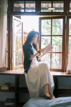 Young woman reads by a sunny window, embracing tranquility and reflection.. young, woman, reads