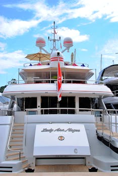 Elegant yacht docked in Monaco harbor under a vibrant sky.