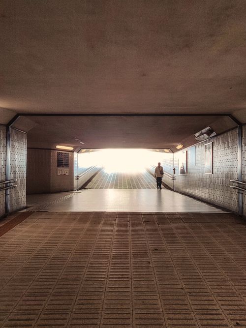 Free A lone pedestrian in a dramatic, well-lit Tokyo tunnel, showcasing urban architecture. Stock Photo