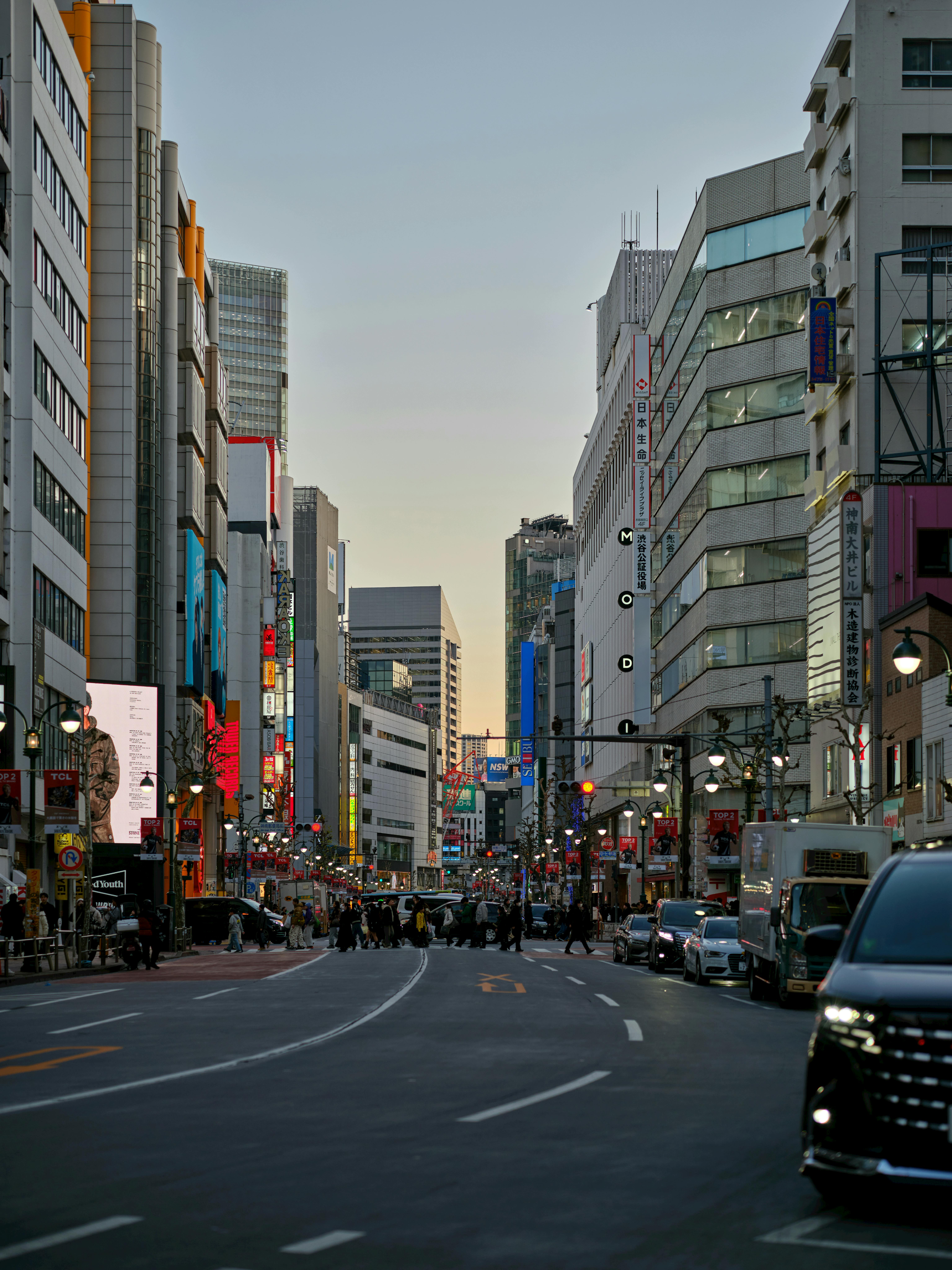 無料 高層ビルと夕暮れ時の鮮やかな光が広がる、東京の賑やかな都会の街路風景。 写真素材