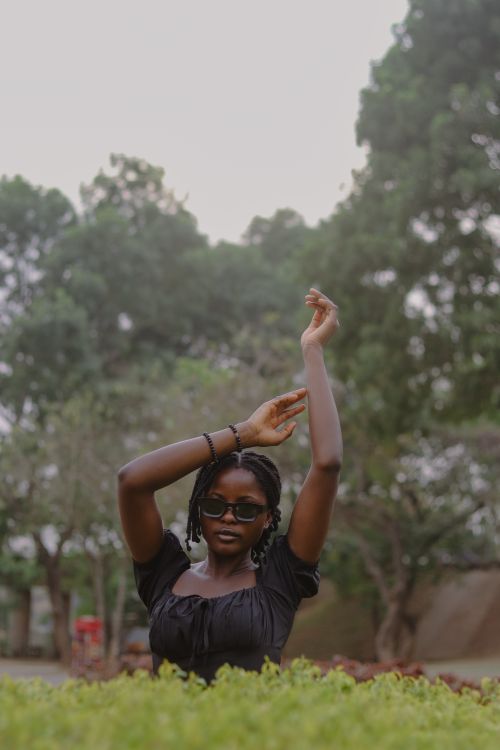 Free Confident woman in sunglasses posing gracefully in a lush outdoor setting. Stock Photo