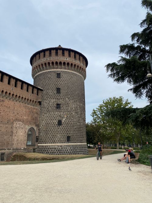 Free People cycling and relaxing by the historic Sforza Castle in Milan. Stock Photo