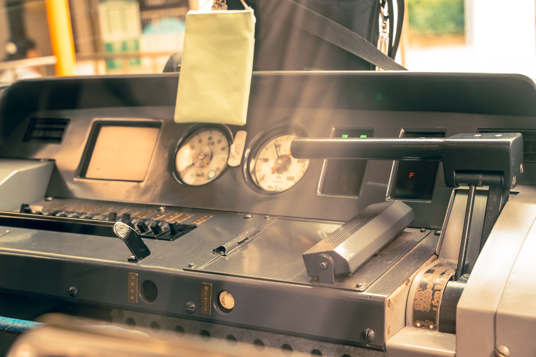 Interior view of a vintage train cockpit at Kamakura Station, showcasing levers and gauges with sunlight streaming in.