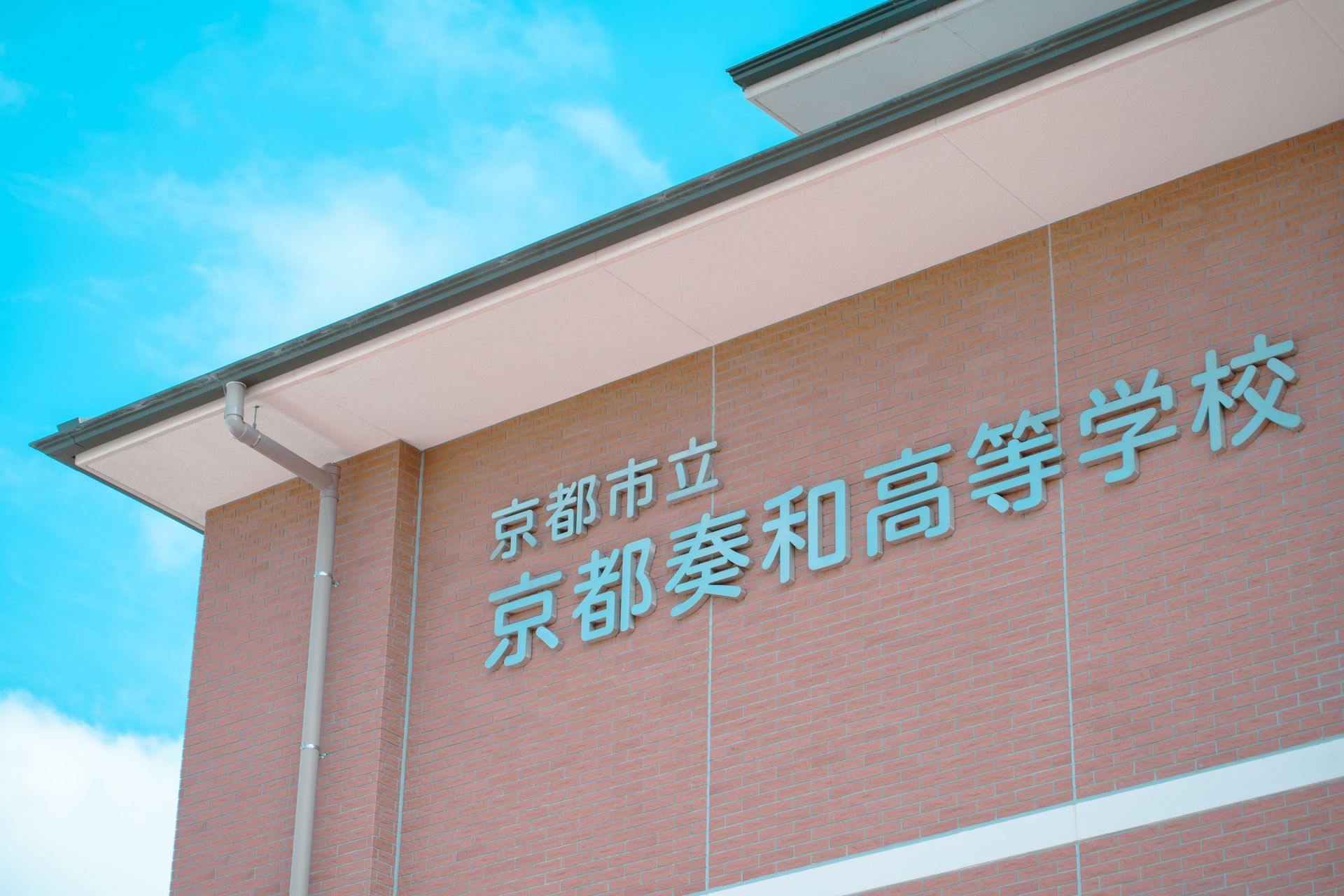 Brick building facade with Japanese text under a clear blue sky in Kyoto, Japan.
