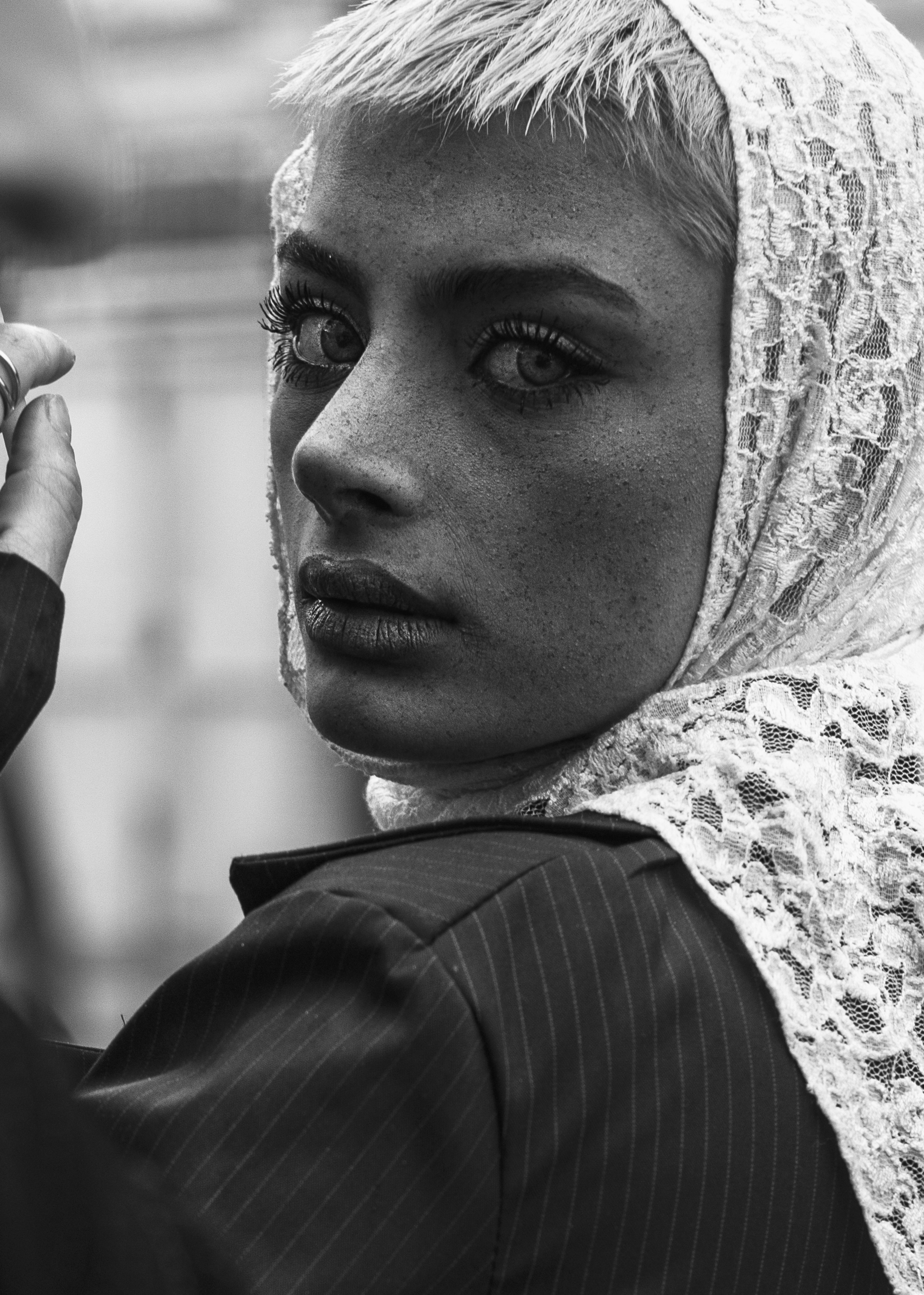 Black and white portrait of a woman wearing a lace headscarf, looking back.