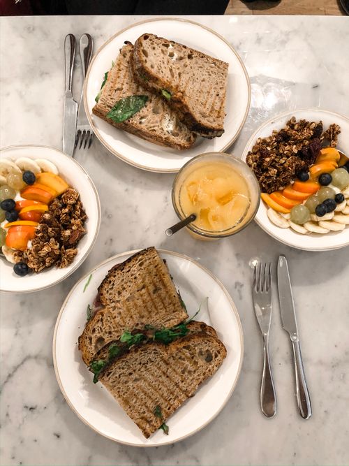 Free Top view of a healthy breakfast with granola bowls, sandwiches, and juice on a marble table. Stock Photo
