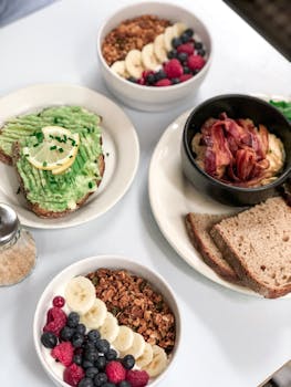 High angle view of a delicious breakfast spread with avocado toast, fruit bowls, and bread.