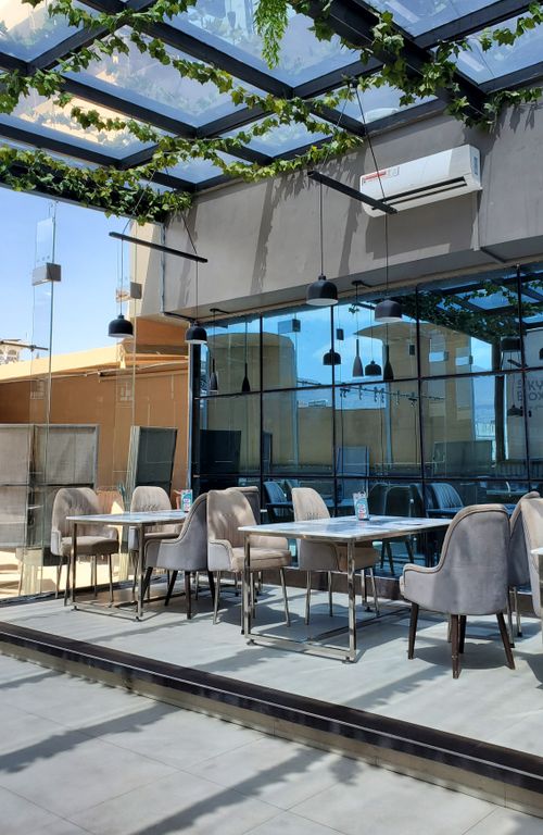 Free Spacious outdoor cafe with glass roof and modern furniture in the sun. Stock Photo