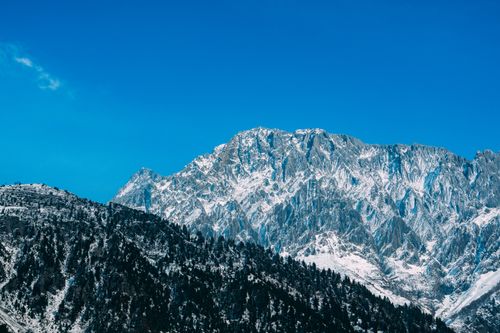 Free Dramatic winter scene of snow-capped mountains against clear blue sky, showcasing nature's beauty. Stock Photo