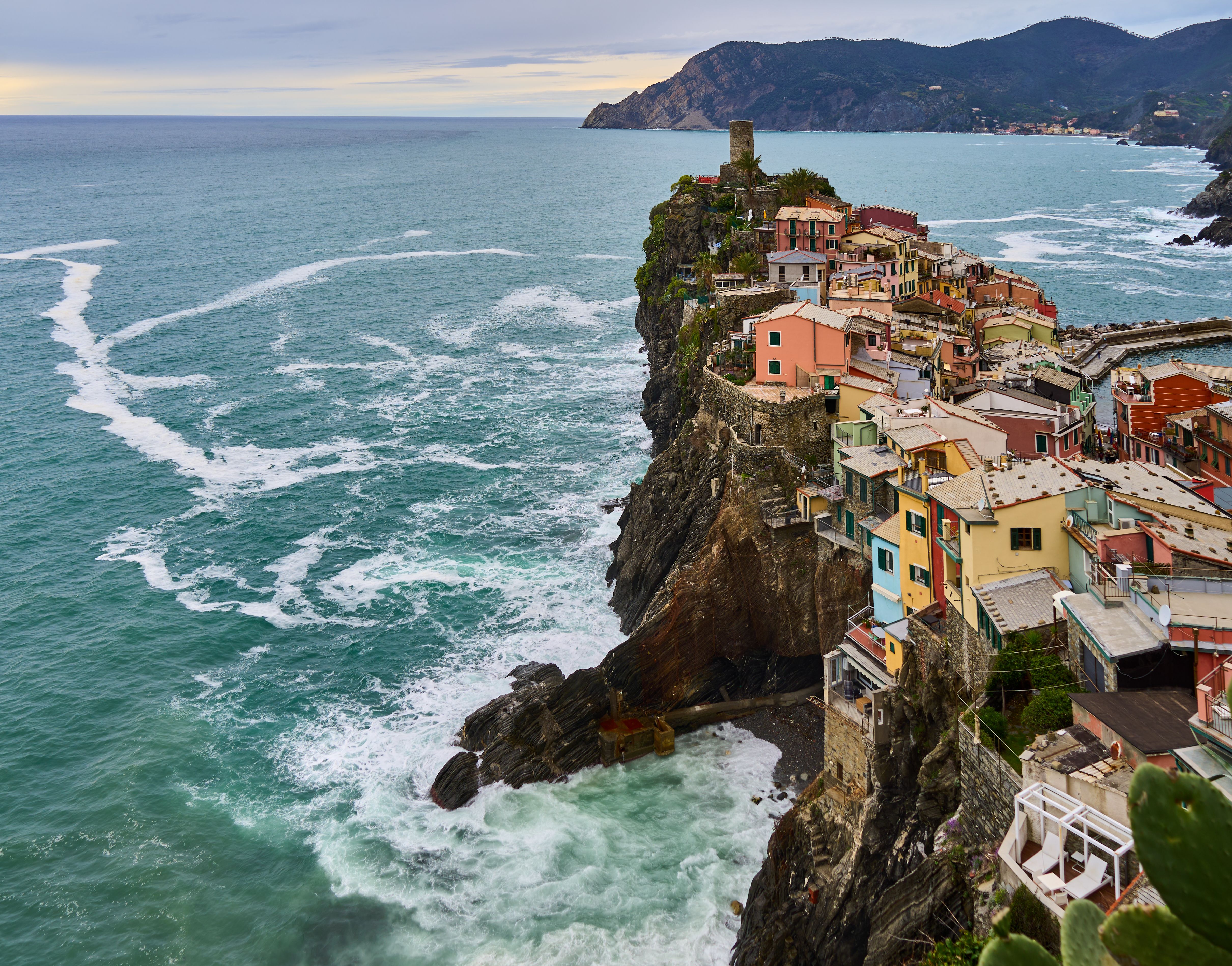 Charming white-washed village overlooking the calm blue Mediterranean Sea in spring with blooming flowers.