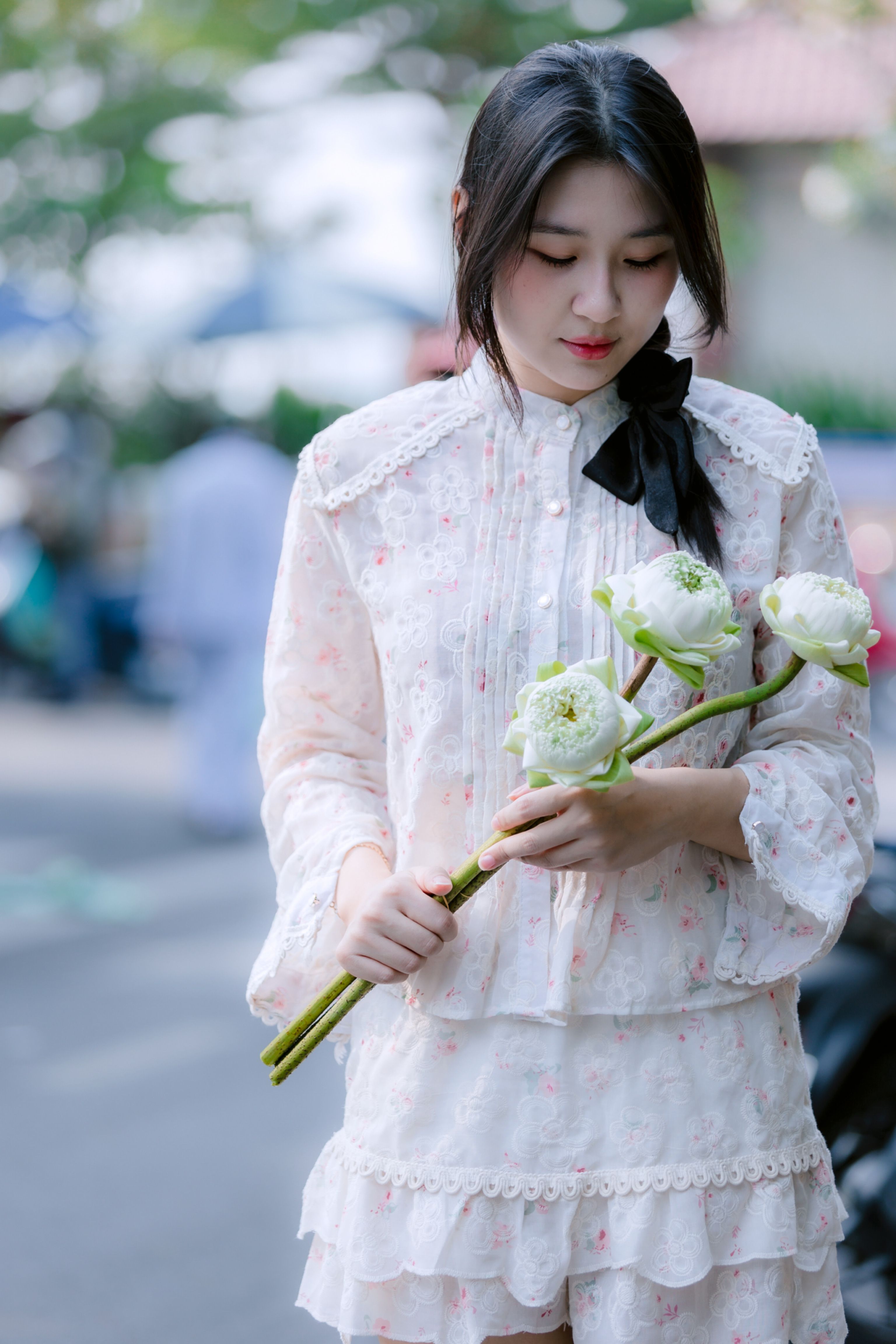 Young Woman in Floral Dress Holding Flowers Outdoors · Free Stock Photo