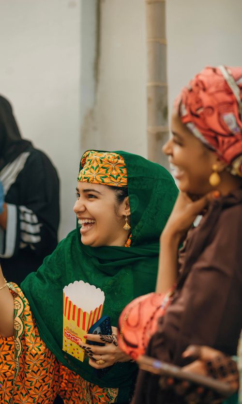 Free Women in colorful attire enjoying festive moments and sharing laughter. Stock Photo