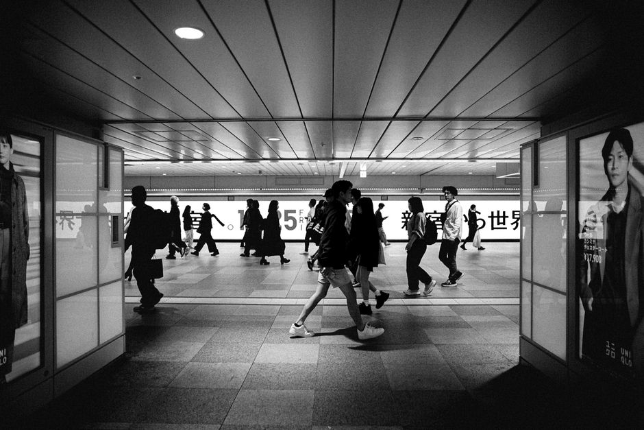 Black and white photo capturing a bustling Tokyo subway station with silhouetted people walking.