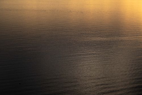 Free Peaceful view of calm sea reflecting golden sunset light, creating a tranquil and serene atmosphere. Stock Photo