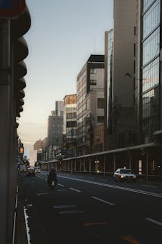 Urban scene of a city street at dusk featuring a motorcyclist and taxis, captured with dramatic lighting.